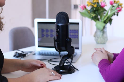 pexels-photo-2041381-2041381 Two women recording a podcast in a modern office with a microphone and laptop.